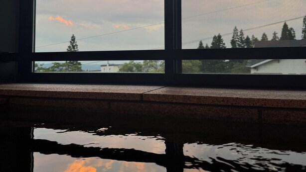 Une fenêtre donnant sur un ciel nuageux, avec le reflet du ciel dans l’eau en contrebas.