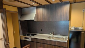 Une cuisine de taille réduite, équipée d’une cuisinière à gaz, d’un évier et d’un réfrigérateur encastré.