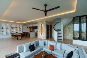 Ein modernes Wohnzimmer mit einer geschwungenen Treppe, einem Essbereich und einer Küche.