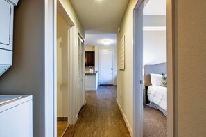 Un couloir d’hôtel avec un coin cuisine et une chambre.