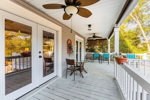 A covered porch with a table and chairs, ceiling fans, and a view of the outdoors. - Charming 3-Bed Beach House with bathtub and BBQ (Surfside Beach)