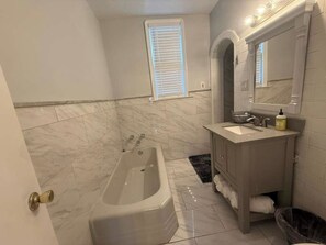 Ein Badezimmer mit Badewanne, Waschbecken, Spiegel und Fenster.