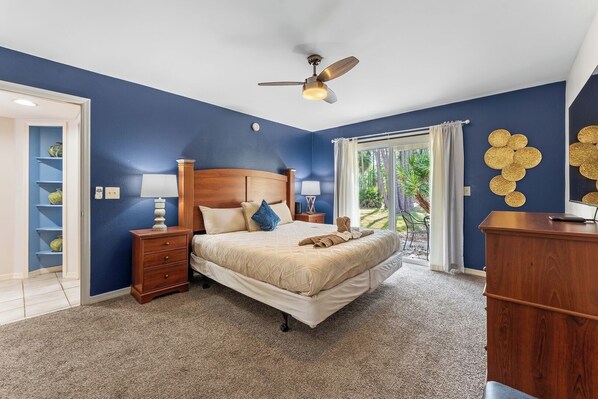 Een slaapkamer met een bed, nachtkastjes, een plafondventilator en uitzicht op de omgeving.