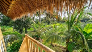 A bamboo railing overlooking a lush garden with palm trees and a thatched roof structure. - Green Harmony Villas (Gianyar)