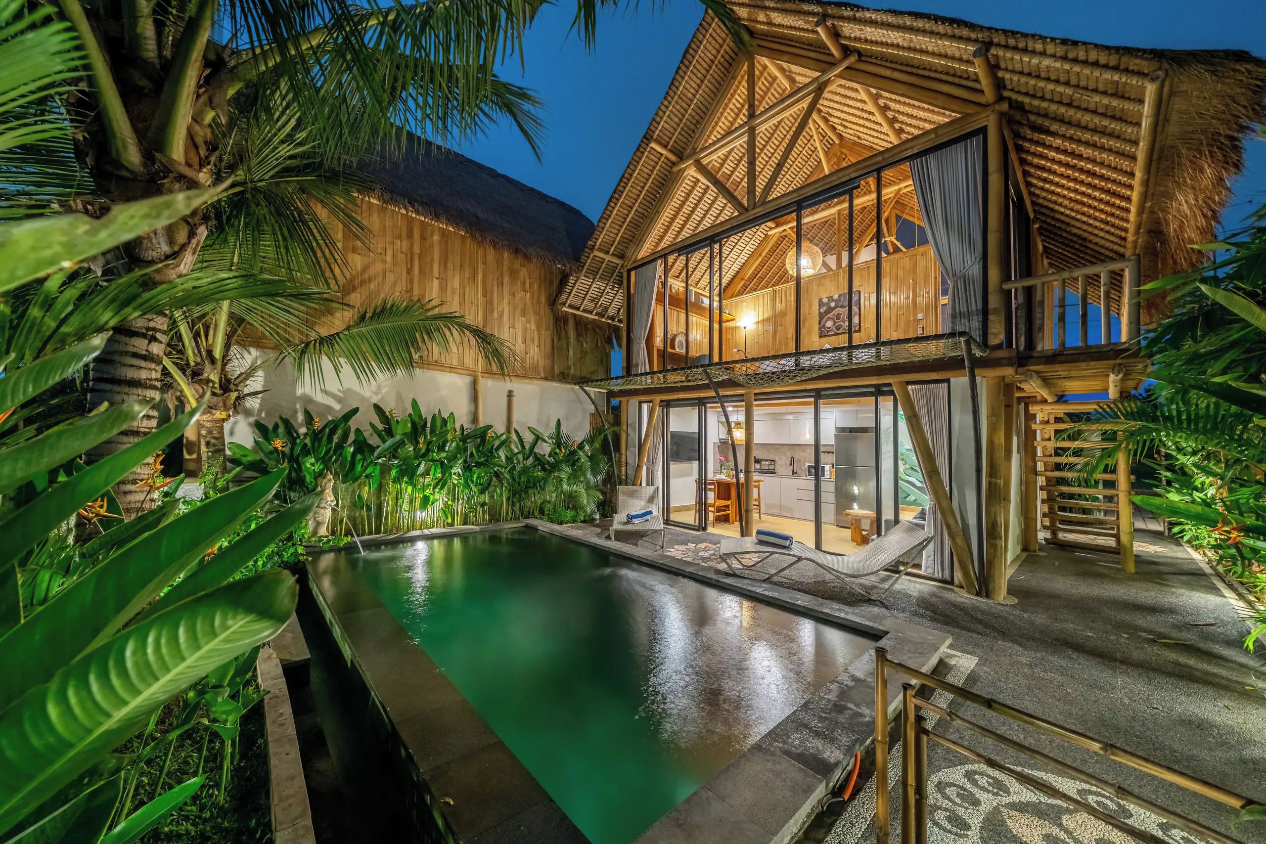 Un resort con piscina, construcciones de madera y vegetación tropical.