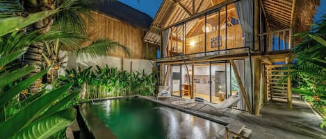 Un resort con piscina, construcciones de madera y vegetación tropical.