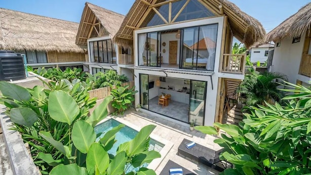 A modern villa with a large glass front, a pool, and lush tropical vegetation. - Green Harmony Villas (Gianyar)
