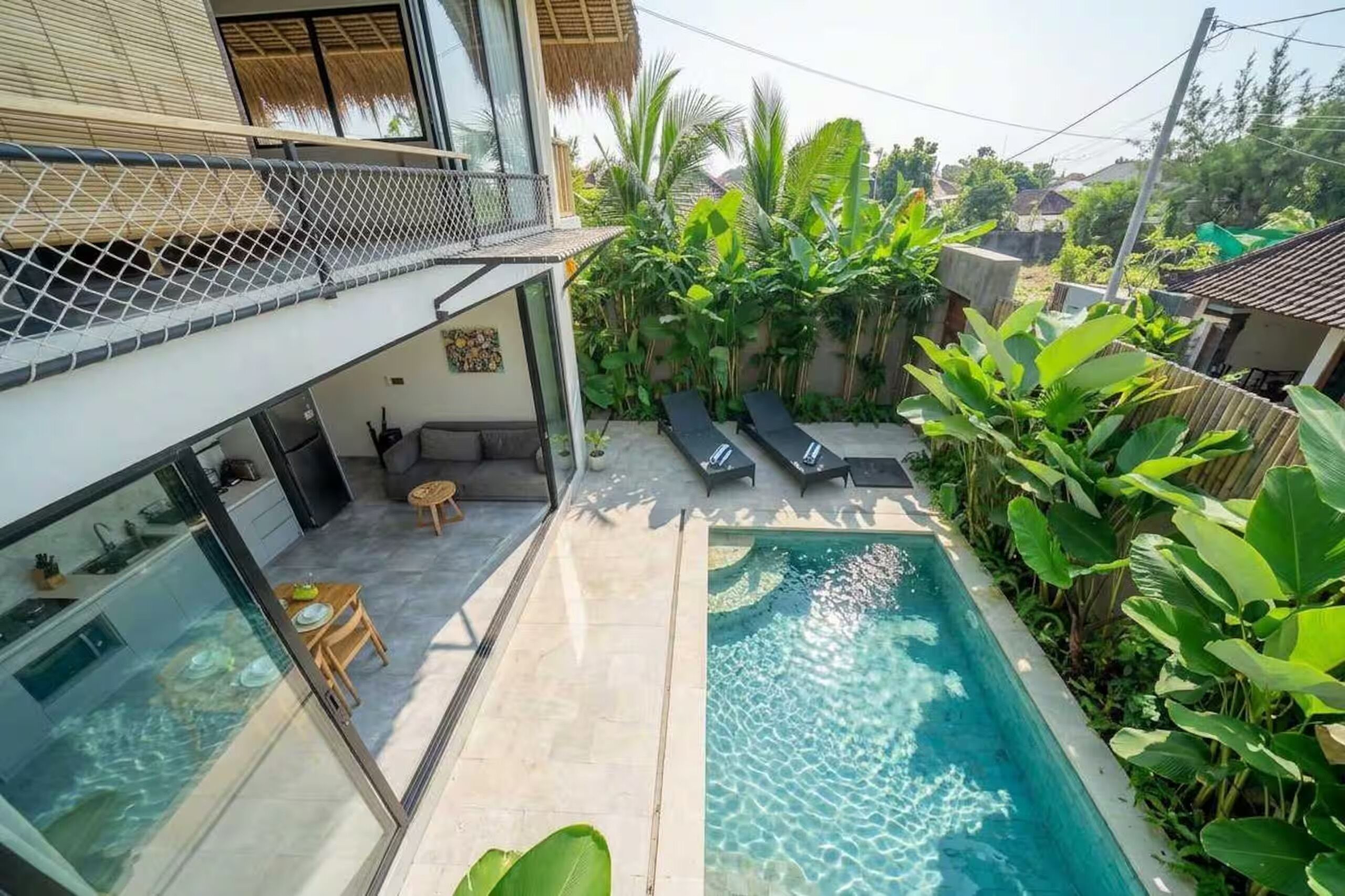 Une maison moderne dotée d’une piscine, d’un coin repas et d’une végétation luxuriante.