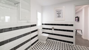 Ein modernes Badezimmer mit einem schwarz-weißen Schachfußboden, einer Toilette und einem Duschbereich.