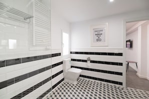 Casa de banho moderna com chão quadriculado em preto e branco, sanita e zona de duche.
