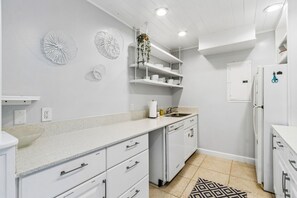 A modern kitchen with white cabinetry, a granite countertop, and a built-in dishwasher. - 3BR Condo - Near Main Beach - Community Pool (Fernandina Beach)