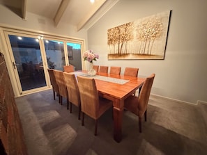A dining area with a wooden table, six chairs, and a vase with flowers.