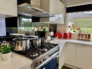 A modern kitchen with stainless steel appliances, a gas stove, a coffee maker, and a red toaster.