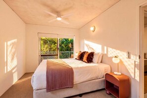A bedroom with a bed, a nightstand, a ceiling fan, a window, and a door. - Picture Point Penthouse 12 - Renovated Coastal Retreat with Sunset Views (Noosa)
