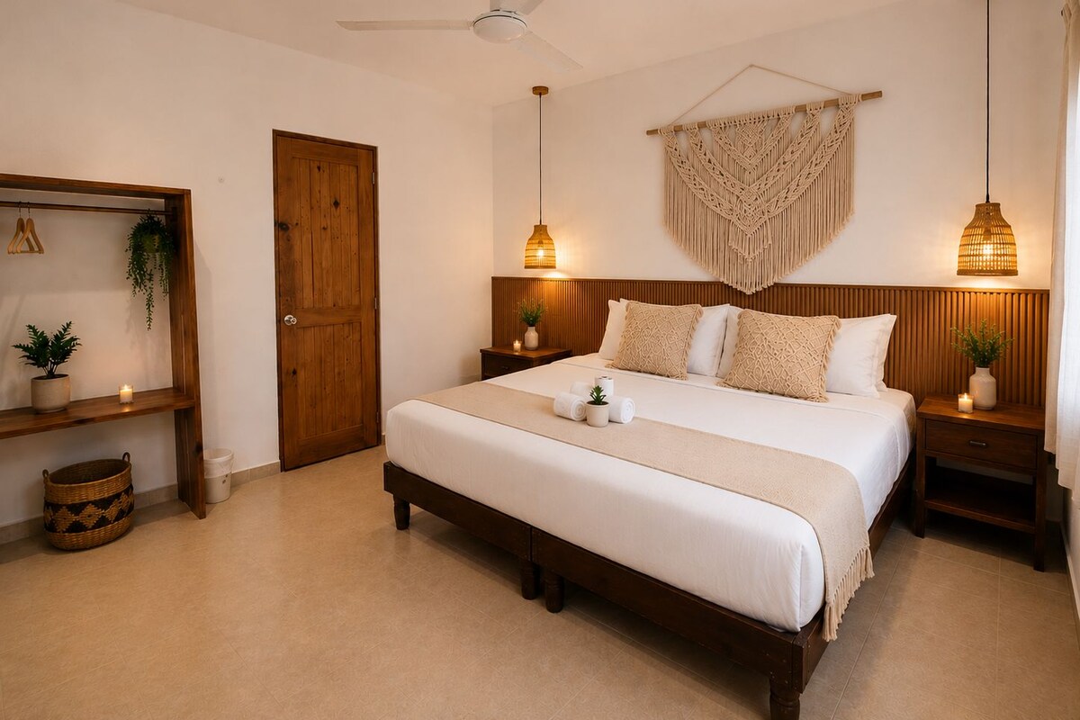 A bedroom with a large bed, wooden headboard, two bedside tables, a ceiling fan, and a macrame wall hanging.