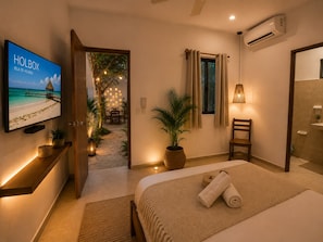 A hotel room with a bed, a TV, a potted plant, a chair, and a bathroom. - Hotel Holbox Centro (Isla Holbox)