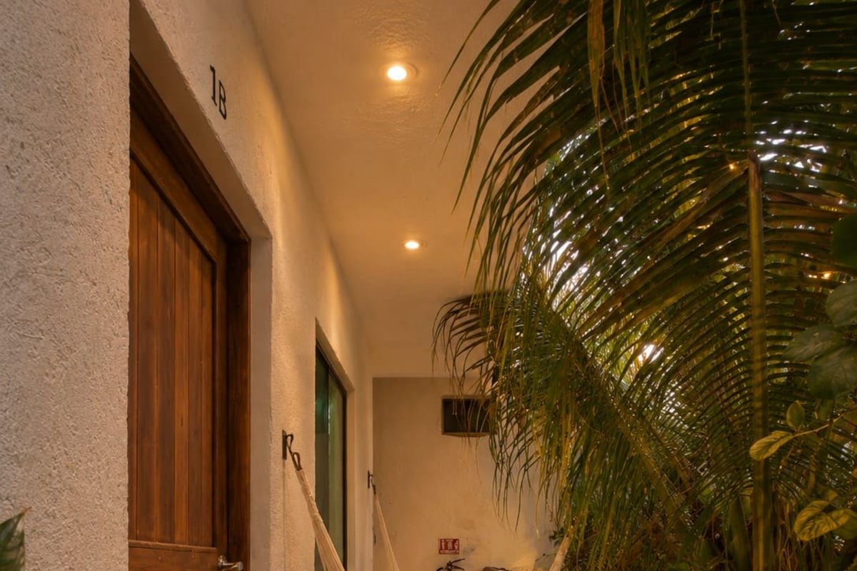 A hallway with a wooden door, a hammock, and a fire extinguisher on the wall.