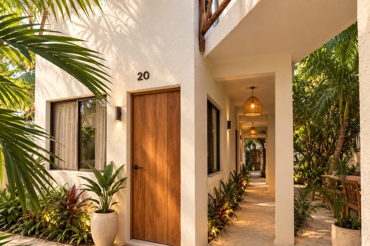 A modern house with a wooden door, number 20, and a pathway leading to a covered area with plants.