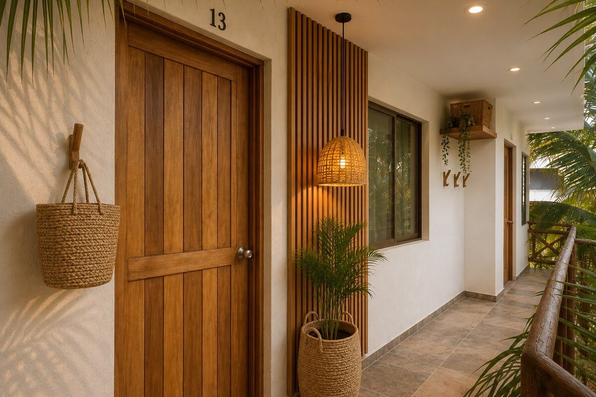A hallway with a wooden door labeled '13', a woven basket hanging on the wall, a woven floor lamp, and a potted plant.
