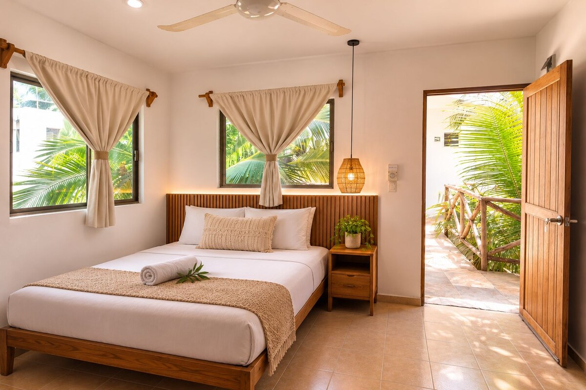 A bedroom with a bed, nightstands, a ceiling fan, and a view of the outdoors.