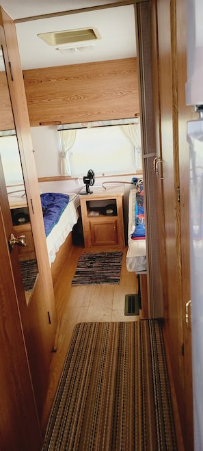A compact, well-lit room with a bed, a small desk, and a fan.