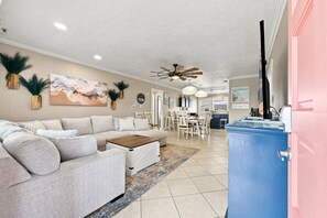 A spacious living room with a large sofa, a coffee table, and a dining area with chairs and a table. - Silver Sand Dollar | Upscale 6BR Escape-Hot Tub (North Myrtle Beach)