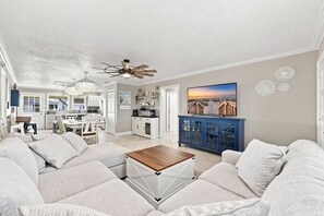 Ein geräumiges Wohnzimmer mit einem großen Ecksofa, einem Couchtisch und einem Fernseher auf einem blauen Schrank.
