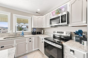 A kitchen with white cabinetry, a built-in microwave, a stove, and a sink. - Silver Sand Dollar | Upscale 6BR Escape-Hot Tub (North Myrtle Beach)