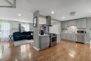 A modern kitchen with grey cabinets, a stainless steel range, and a built-in microwave. - Modern 4BR Retreat Spacious Living, Fireplace & Finished Basement (Matteson)