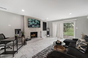 A modern living room with a fireplace, a flat-screen TV, and a sofa. - Modern 4BR Retreat Spacious Living, Fireplace & Finished Basement (Matteson)