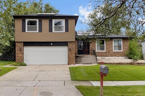 A two-story house with a garage, a mailbox, and a small attached garage. - Modern 4BR Retreat Spacious Living, Fireplace & Finished Basement (Matteson)