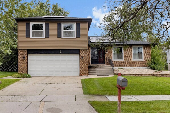 A two-story house with a garage, a mailbox, and a small attached garage. - Modern 4BR Retreat Spacious Living, Fireplace & Finished Basement (Matteson)