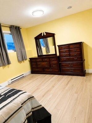 A bedroom with a bed, a dresser, a mirror, and a window with curtains. - Luxurious Apartment in St. John’s (St. John's)