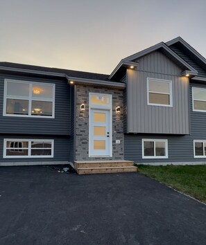 A two-story house with a stone facade, a white front door, and a small porch. - Luxurious Apartment in St. John’s (St. John's)