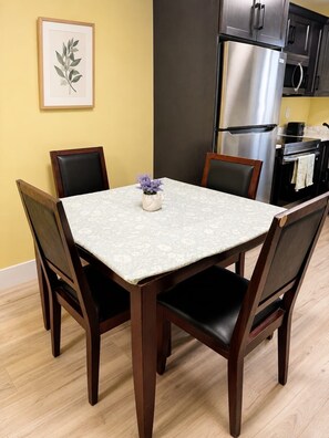 A dining table with four chairs, a vase with flowers, and a framed botanical print on the wall. - Luxurious Apartment in St. John’s (St. John's)