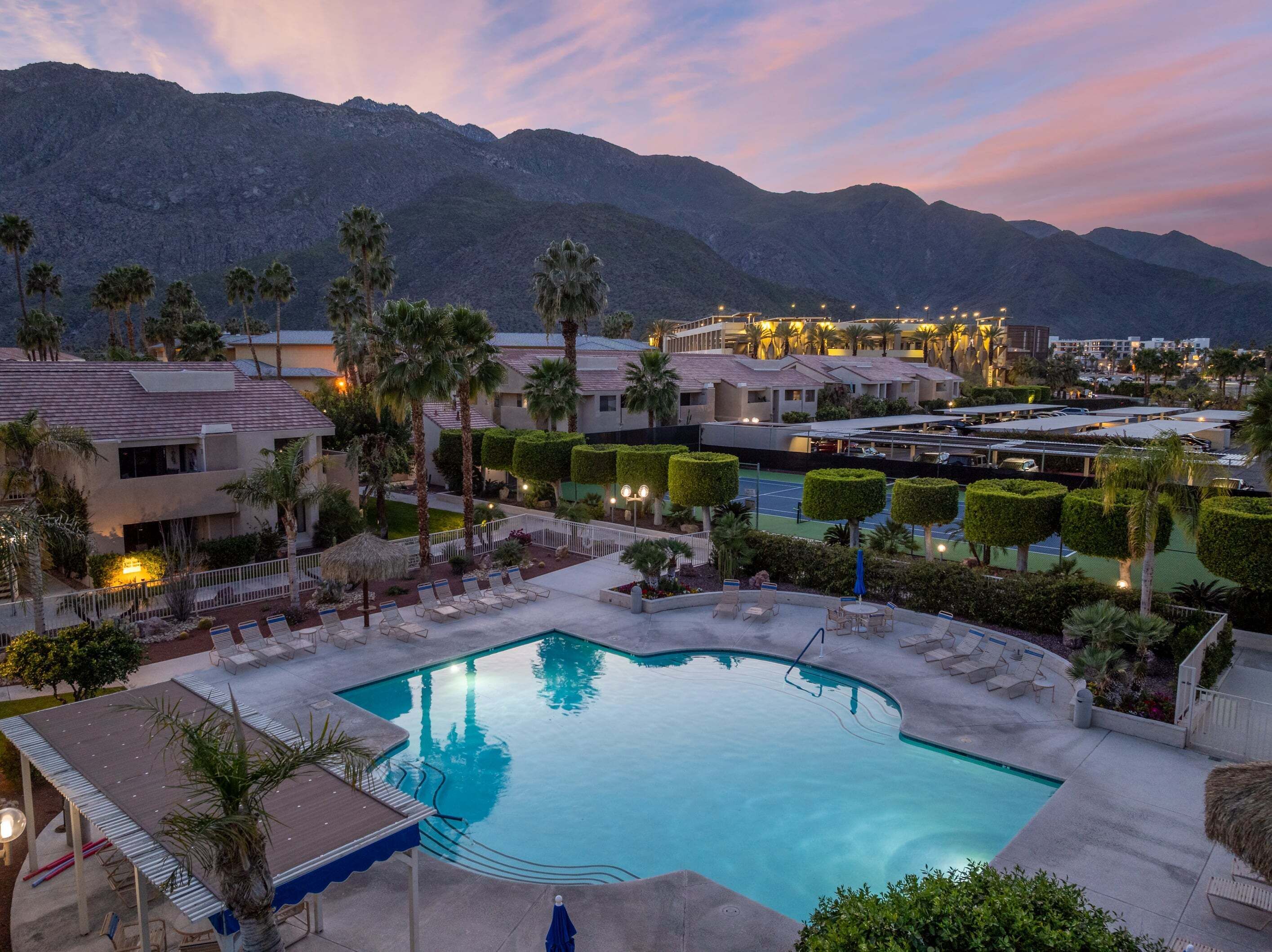 Un resort con piscina, sillas de descanso y montañas al fondo.