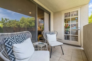 A balcony with wicker furniture and a glass door leading inside. - Casa del Segundo | MCM 1BR | 2 Pools & Tennis | Palm Springs (Palm Springs)