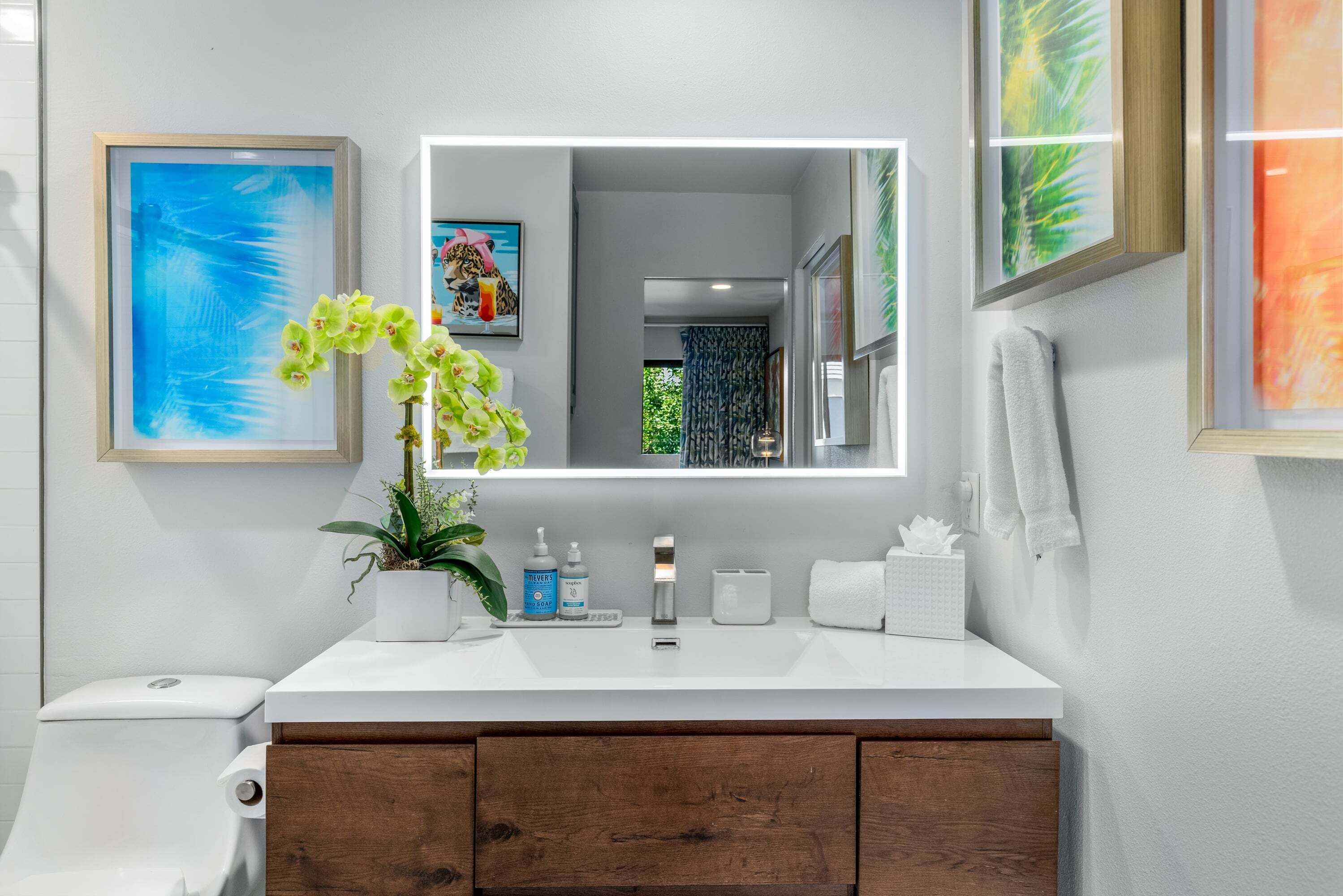 A modern bathroom with a white vanity, a mirror, and a toilet.
