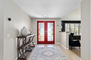 A hallway with a red door, a white wall, a wooden bench, and a patterned rug. - Boqueron and Beyond | Private Pool & Spa | Entertainer's Backyard | 3BR | Bermuda Dunes (Bermuda Dunes)