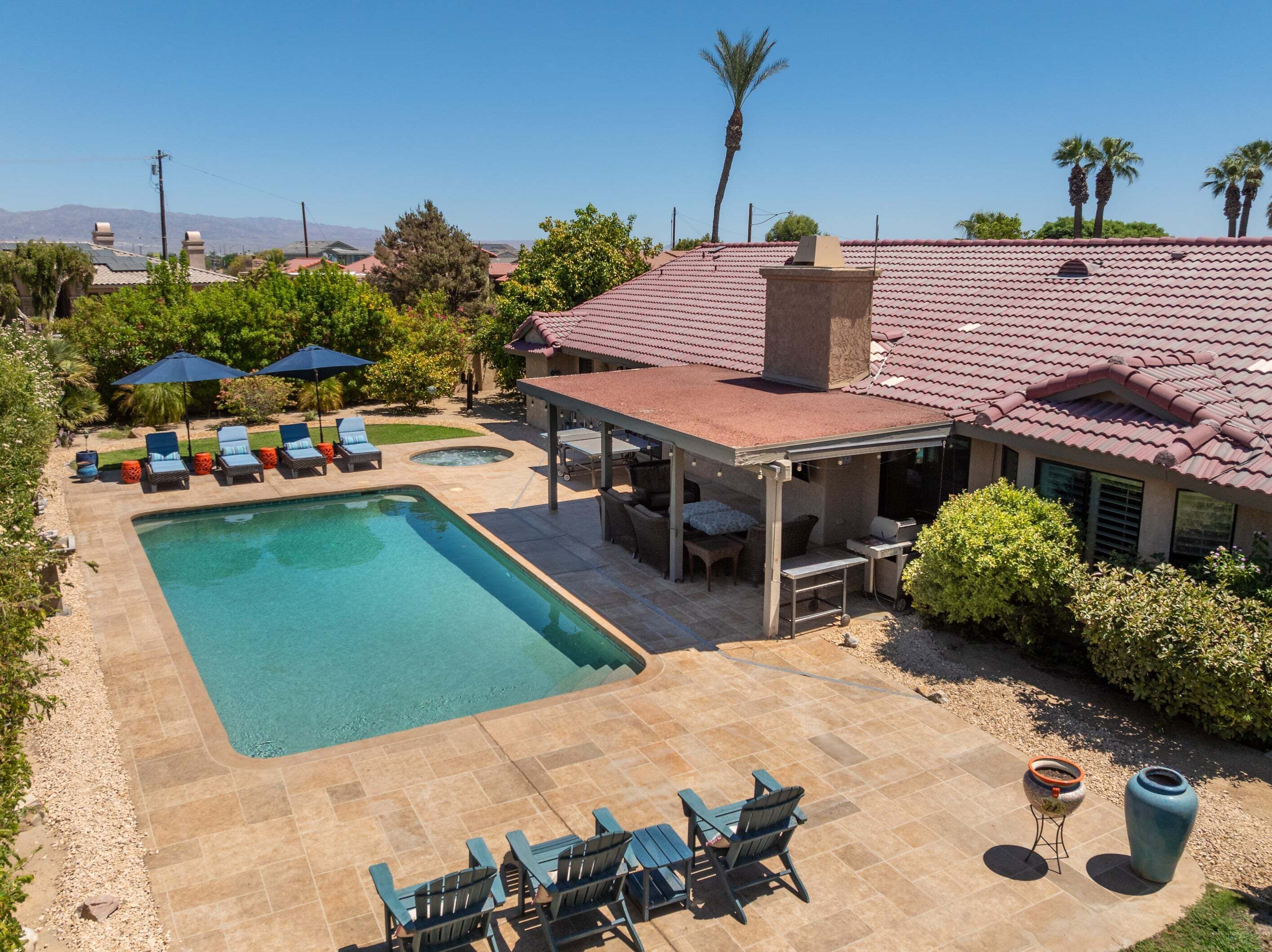 A backyard with a swimming pool, outdoor seating, and a patio area.