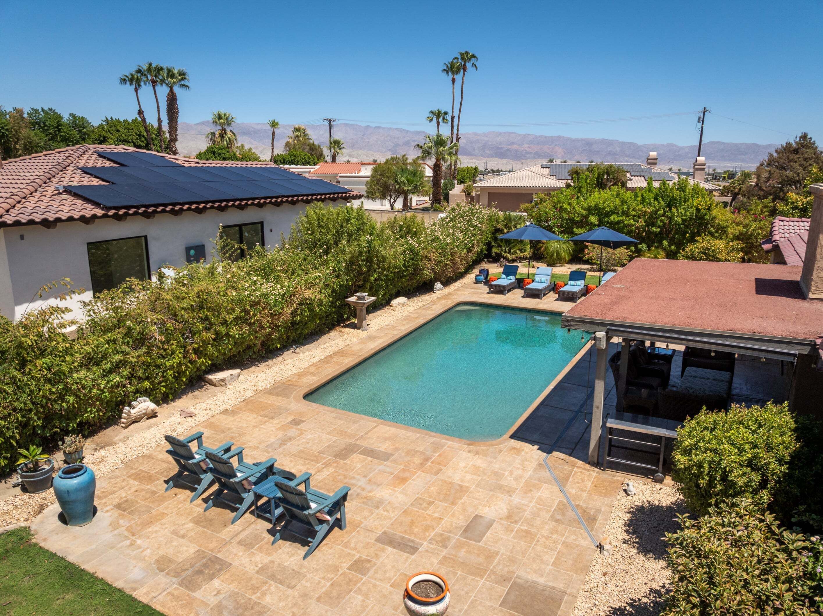 A residential area with a swimming pool, lounge chairs, and a barbecue area.