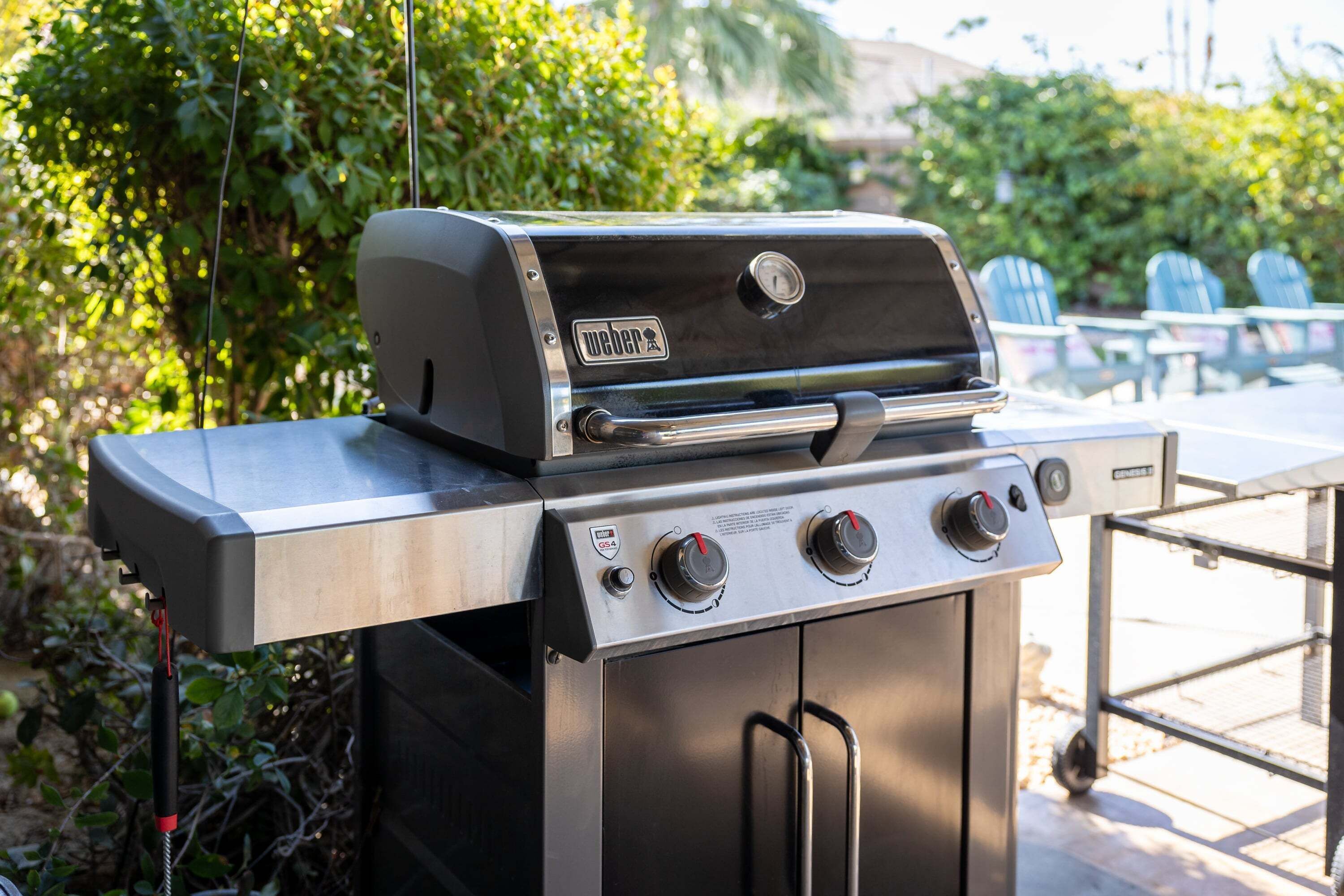 A Weber GS4 gas grill with a stainless steel finish, a digital thermometer, and a side burner.