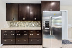 A kitchen with dark wooden cabinets, a stainless steel refrigerator, and a tiled backsplash. - Boqueron and Beyond | Private Pool & Spa | Entertainer's Backyard | 3BR | Bermuda Dunes (Bermuda Dunes)