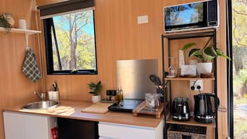 A compact kitchen with a sink, a microwave, and a window with a view of trees.