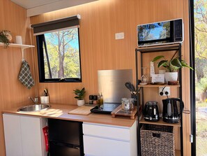 Una cucina compatta con lavello, forno a microonde e una finestra vista alberi.