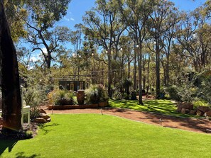 A well-maintained garden with a lawn, trees, and a small building.