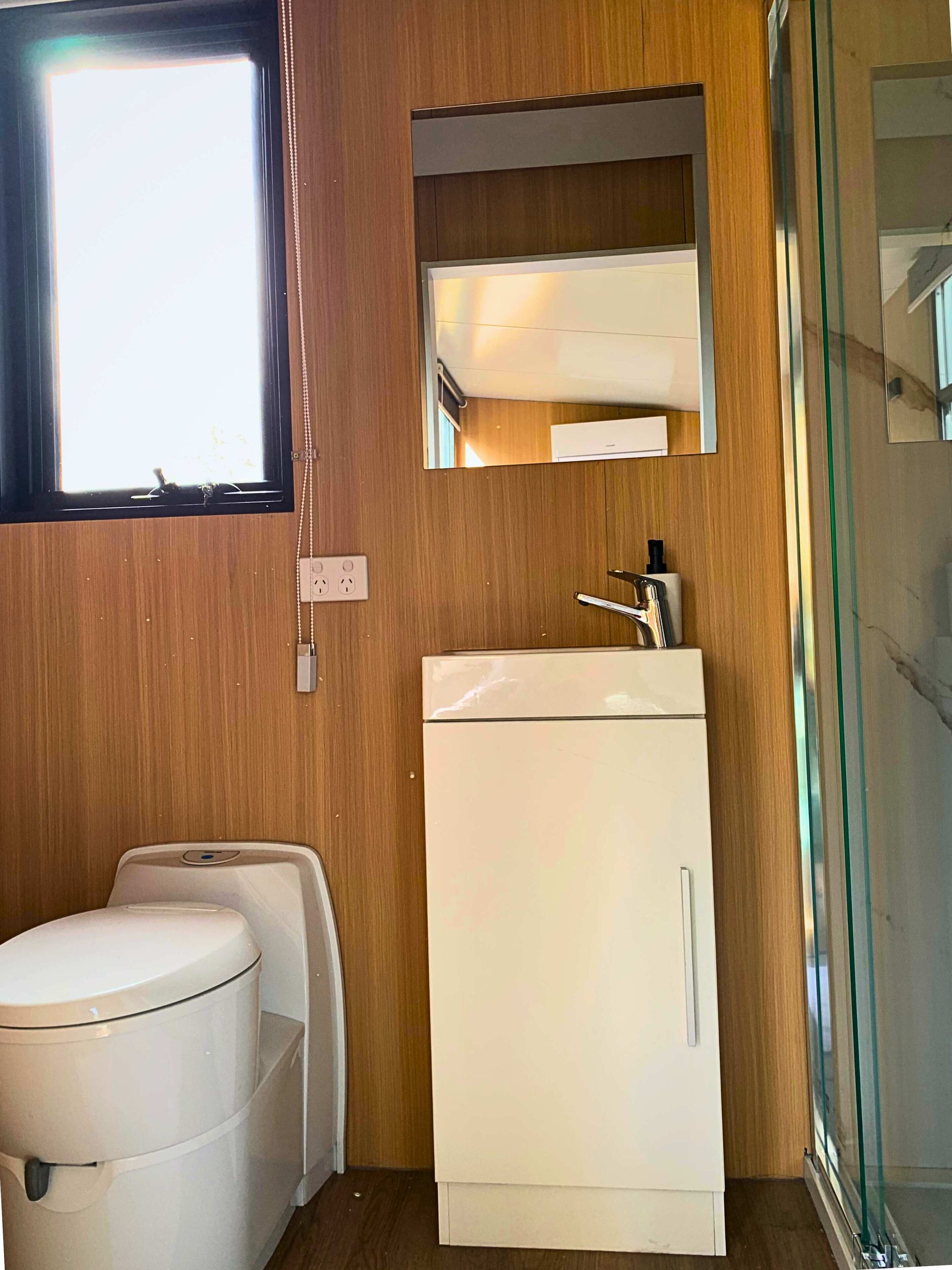 Een kleine badkamer met toilet, wastafel en spiegel.