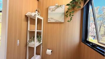 Eine Holzwand mit einer weißen Regaleinheit, einem gerahmten Bild und einer hängenden Pflanze.