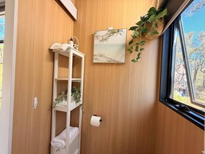 Una parete in legno con un ripiano bianco, un quadro incorniciato e una pianta sospesa.
