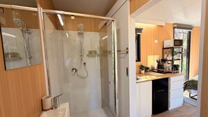 A modern bathroom with a glass-enclosed shower, a sink, and a mirror.